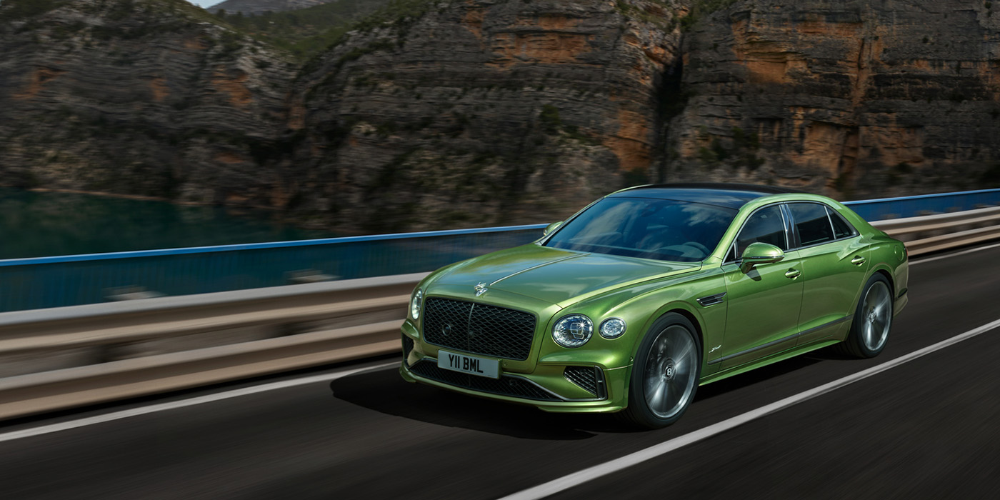 Bentley Porto Bentley New Flying Spur Speed v8 hybrid sedan driving dynamically on a mountain road in Tourmaline Green paint
