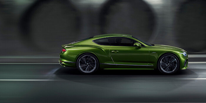  Bentley Porto Bentley Continental GT coupe in Tourmaline Green paint driving in profile on a dark road