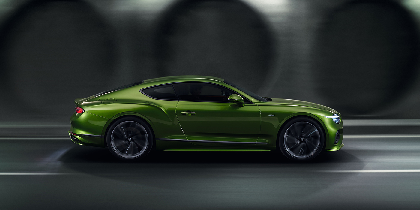 Bentley Porto Bentley Continental GT coupe in Tourmaline Green paint driving in profile on a dark road